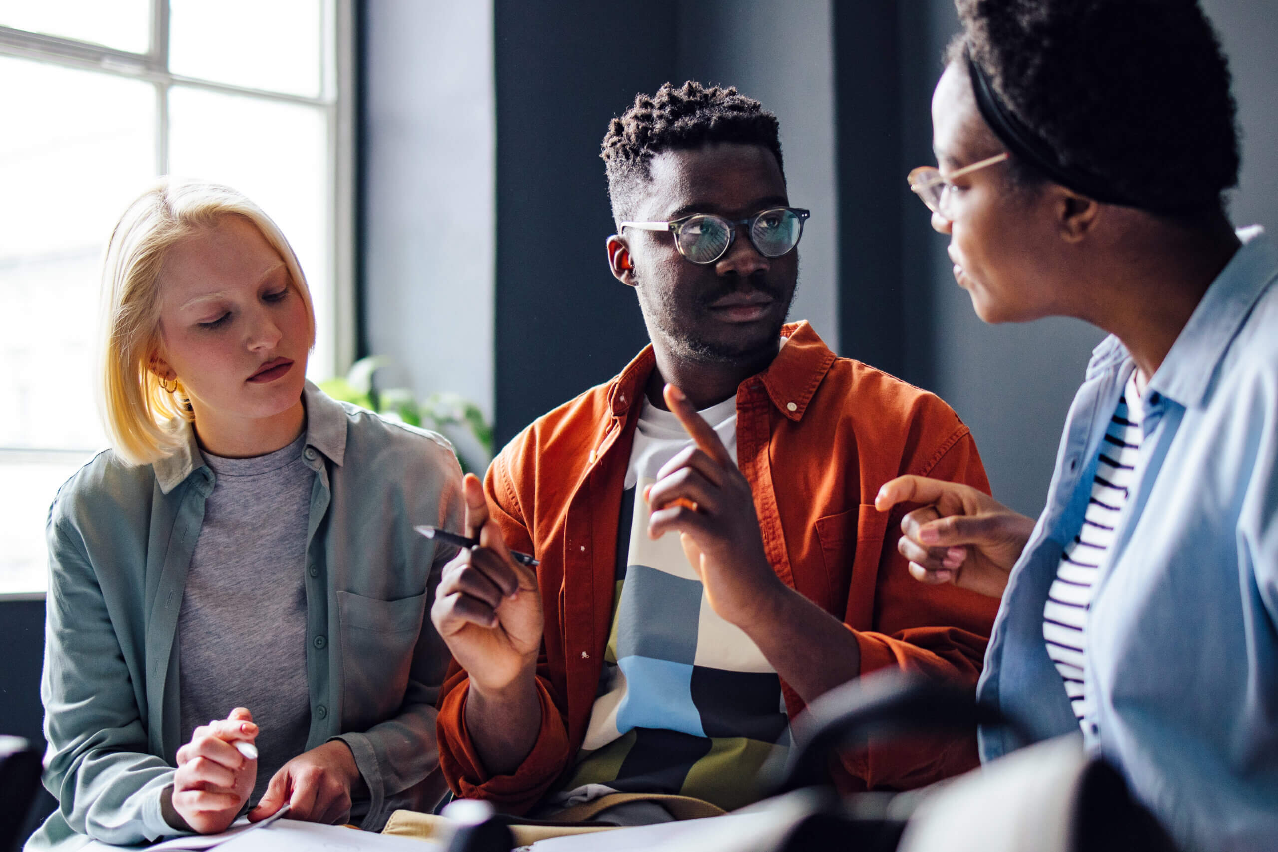 Serious African-American student explains something to his multi ethnic group of friends.